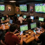 Patrons engaged in live sports betting at BL555 with multiple screens displaying matches.